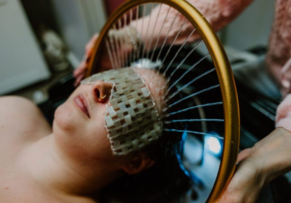 Person with woven eye mask under circular frame