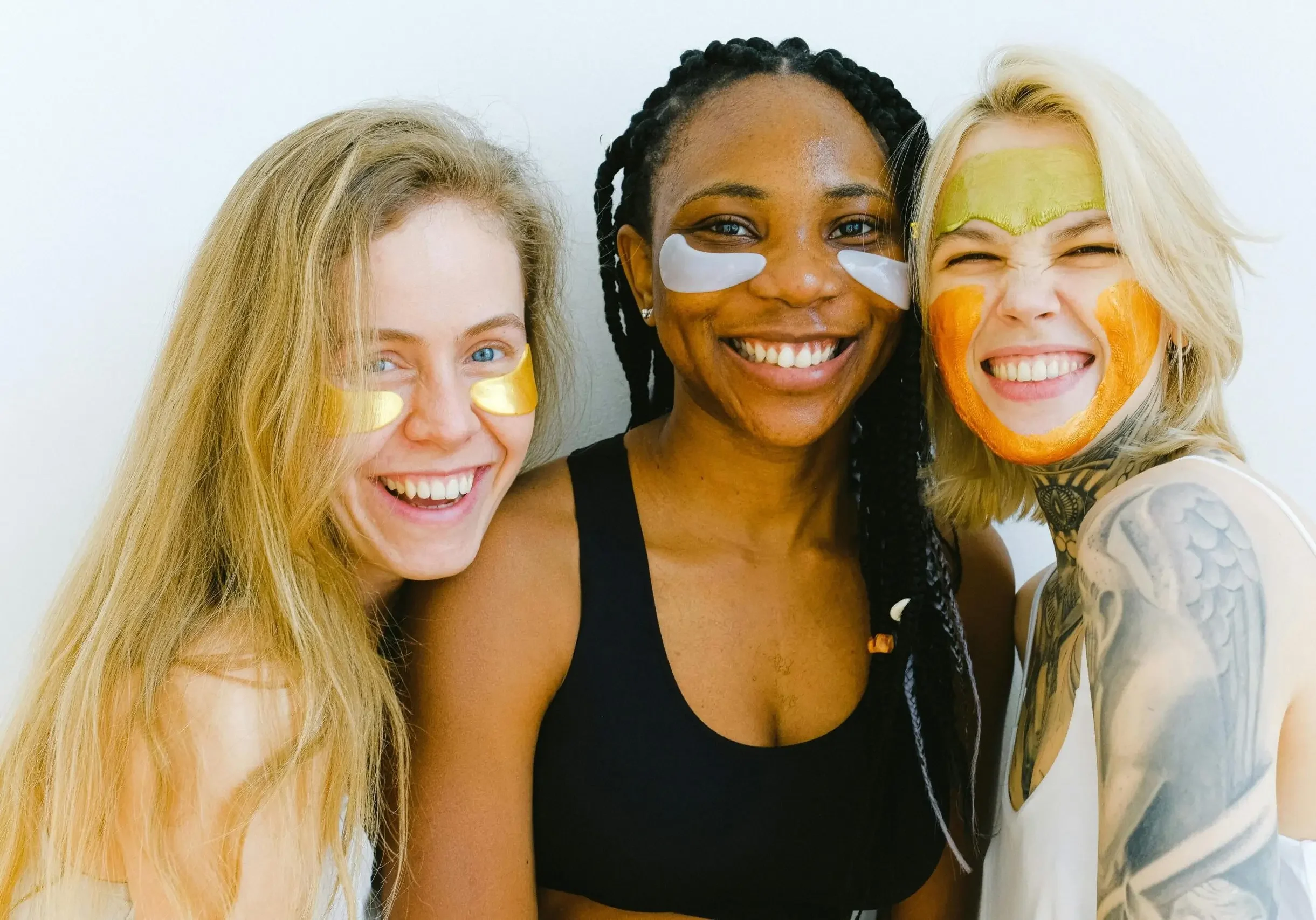 Three women smiling and posing closely together.